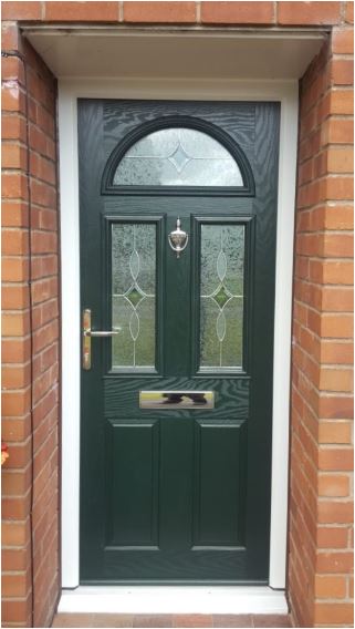 Dark green Residor composite front door with decorative glazed panels and a semi-circular top window, framed by red brickwork and featuring a chrome knocker and letterbox.