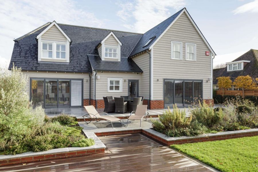 Modern home with cream-painted timber windows and doors, featuring sliding patio doors and decorative gable windows.